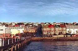 A wharf with warehouses on the left; on the right are two-storey brick houses. Similar two-storey houses line the streets beyond.