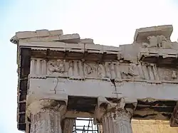 Bâtiment antique : haut des colonnes; entablement avec métopes et toit.