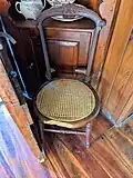 Chair in living room, with beaver gnaw marks on the front of the seat.