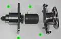 A partially disassembled CBM Powered Bolt, showing both ends of the shaft (1), the lower housing (2) that nestles into the ACBM ring, the drive sleeve (3) and its spline interface with the shaft, and the upper housing (4). The upper housing and drive sleeve can be removed without demating the vestibule to install a spline lock under an IVA seal "butter dish". The spline lock prevents the bolt from backing out.[6][119]