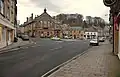 Junction near a busy town centre, with a town hall and nearby shops by the side of the road.