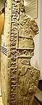 A broken stone prism with inscriptions and hand-shaped reliefs.