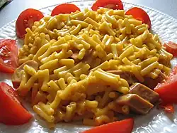 A Canadian meal—Kraft Dinner with added Cheddar that has been integrated with sliced vegetarian hot dog and fresh tomato slices