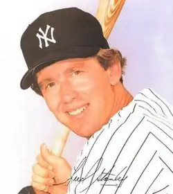 A man in a white jersey and navy cap