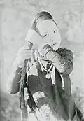 Woman tying her hair up. She is seen wearing a kiềng.