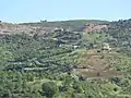 Hillside village in Kurdistan with winding roads connecting homes, fields, and rugged greenery