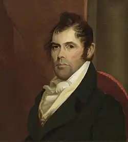 A man with thick, black hair wearing a white shirt and dark jacket