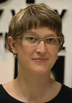 A smiling 35-year-old woman with brown and blonde hair