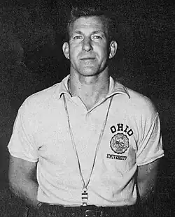 Jim Snyder is posing with a University of Ohio polo shirt