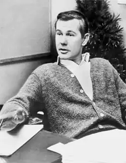 A black-and-white image of Johnny Carson sitting at a desk.