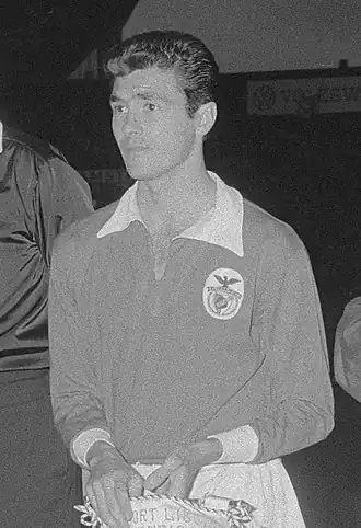 Black-and-white photo of a man donning an association football kit and holding a banner.