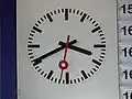 Modern German station clock next to split-flap display board.