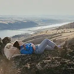 A photo of Cilker lying on a hilltop over a valley