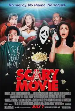 A group of people sitting in a cinema. Among them is a masked figure in black with smiling ghost face mask.