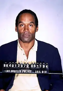 Simpson dressed in a suit, with a number identifier in front of him