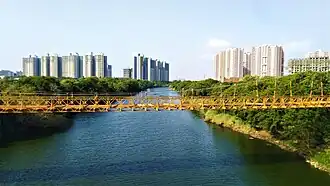 Mula River and its riparian zone as seen from road bridge on Thakar Chowk Mann Road near Mahalunge. A yellow hanging bridge can be seen the center with Blue Ridge Township on the left and VTP Bel Air on the right.