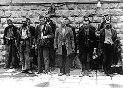 Several men standing in front of a brick wall.