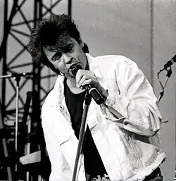 A man is seen singing into a microphone onstage