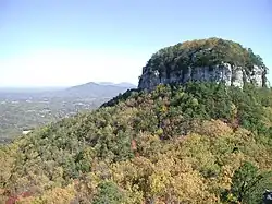 A view in fall of Big Pinnacle from Little Pinnacle Overlook, with Sauratown Mountain and Hanging Rock State Park seen beyond that.
