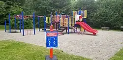 The same playground, re-opened, with signage cautioning that special care should still be taken due to COVID-19.