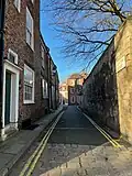 Looking west down the street from in front of No. 1. The southern wall of Purey-Cust Lodge (right) is the only building on the northern side of the street