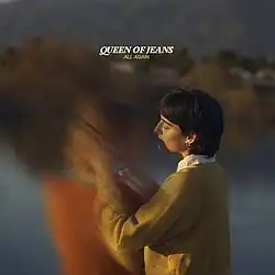 A photo of a woman in a field embracing another person who is blurred