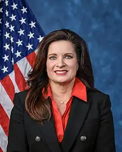 Official House portrait of Biggs smiling in front of the U.S. flag, wearing a black jacket with large silver buttons, red shirt, and silver Virgin Mary necklace.