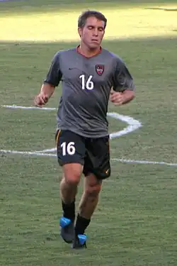 Richie Williams playing for DC United. He is running on a soccer pitch and wearing a grey uniform with the number 16.