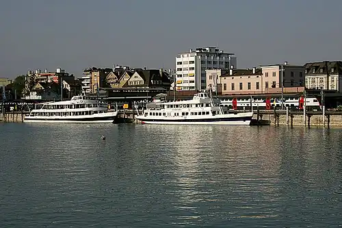 Two boats on a lake in front of a station building