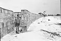 A wind break constructed from ration boxes protecting the small RAF camp at Kelai, Maldive Islands, which served as a refuelling base for flying boats operating in the Indian Ocean