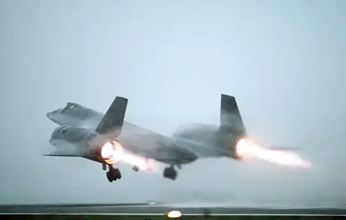 A similar viewing angle, unstick speed 210 knots, to the "exploded" view, and with the same operating configuration: afterburner nozzle open, blow-in doors open and trailing flaps closed due to low internal pressure with low speed low inlet ram. Note the dark con-di shroud. Air entering the blow-in doors joins secondary air from the inlet and flows over the fixed shroud surface and trailing flaps while surrounding the exhaust from the engine.