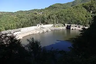 A body of water surrounded by greenery on one side and a concrete structure on the other