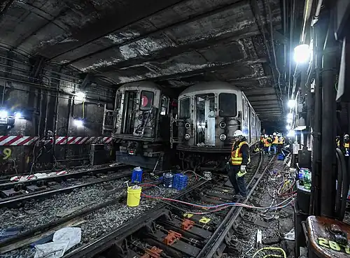 A photo in the subway tunnel of two trains off the rails