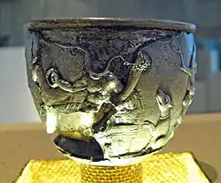 A reclining male figure, with torcs and cornucopia, next to a dog.
