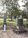 A small memorial within Lang Park, west of Queen street, which commemorates the men and women who worked at the St Marys munitions factory during World War II. A sign is inscribed with the story of the factory's development during the war and the significance of its remnants in the present day; beside the sign is a trolley carrying four bomb shell casings[38]