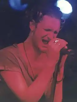 A man in a t-shirt singing into a microphone.