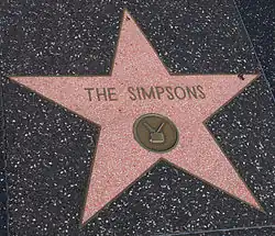 A red star with a small medal inside of it and text that reads THE SIMPSONS.