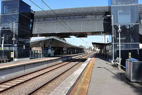 Thomastown station Platform 2 looking south, showing the pedestrian footbridge, station building and shelters