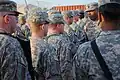 Soldiers with the 94th Military Police Company, Special Troops Battalion, 2nd Advise and Assist Brigade, 1st Infantry Division, places a 1st Infantry Division shoulder sleeve insignia – former wartime service at Camp Liberty, Iraq.