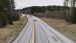 Image of the Finnish Main road 5 with three cars at Kuortti in Pertunmaa. The picture has been taken from the perspective of the bridge at Kuortti's interchange.