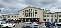 A large, white building, seen from a parking lot