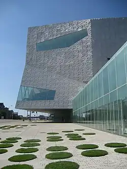 Modern building in bright sunlight with circles of grass in foreground